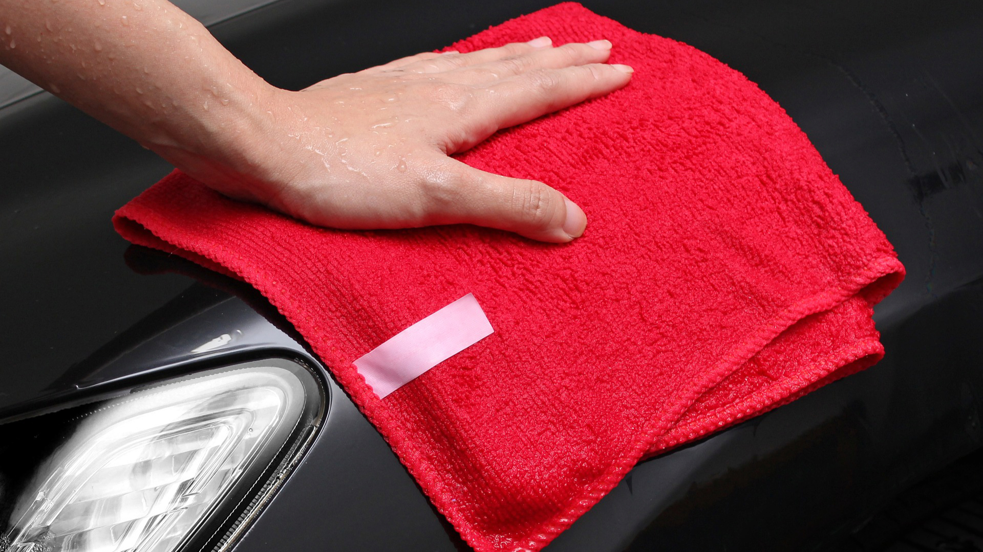 Hand finishing a car with a red microfiber towel during a professional hand wash – car valet service in Dundee.